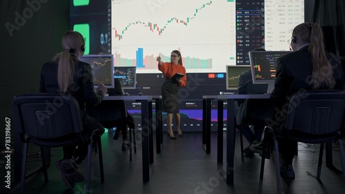 Successful business people in the office. Team of brokers and ceo top manager having meeting in front of big screens with charts talking selling stock.