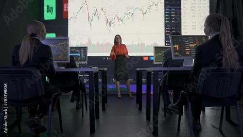 Successful business people in the office. Team of brokers and ceo top manager having meeting in front of big screens with charts talking discussing market data. photo