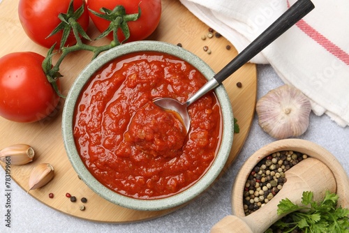 Fototapeta Naklejka Na Ścianę i Meble -  Homemade tomato sauce in bowl, spoon and fresh ingredients on light grey table, flat lay