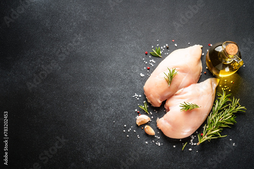 Chicken meat. Raw chicken breast with spices at black table. Top view.