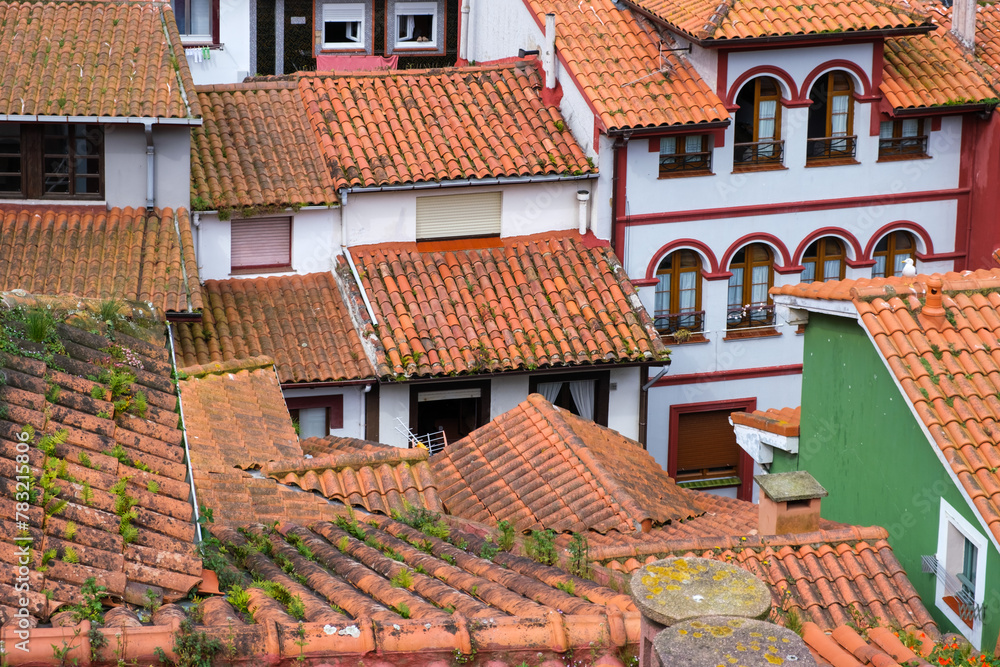 A group of buildings with red and white roofs clustered together in the picturesque coastal town of Cudillero, Asturias, Spain. 