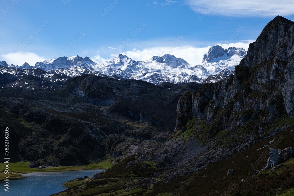 A stunning view of the Lakes of Covadonga in the foreground, with the towering peaks of the Picos de Europa mountain range in the background.