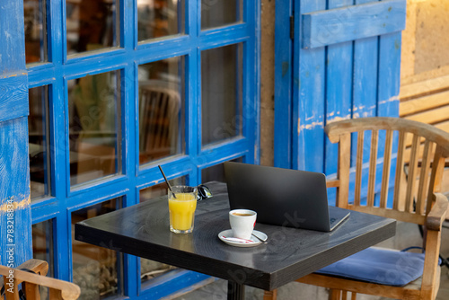 Wooden chairs and tables in a cafe with blue wooden doors.