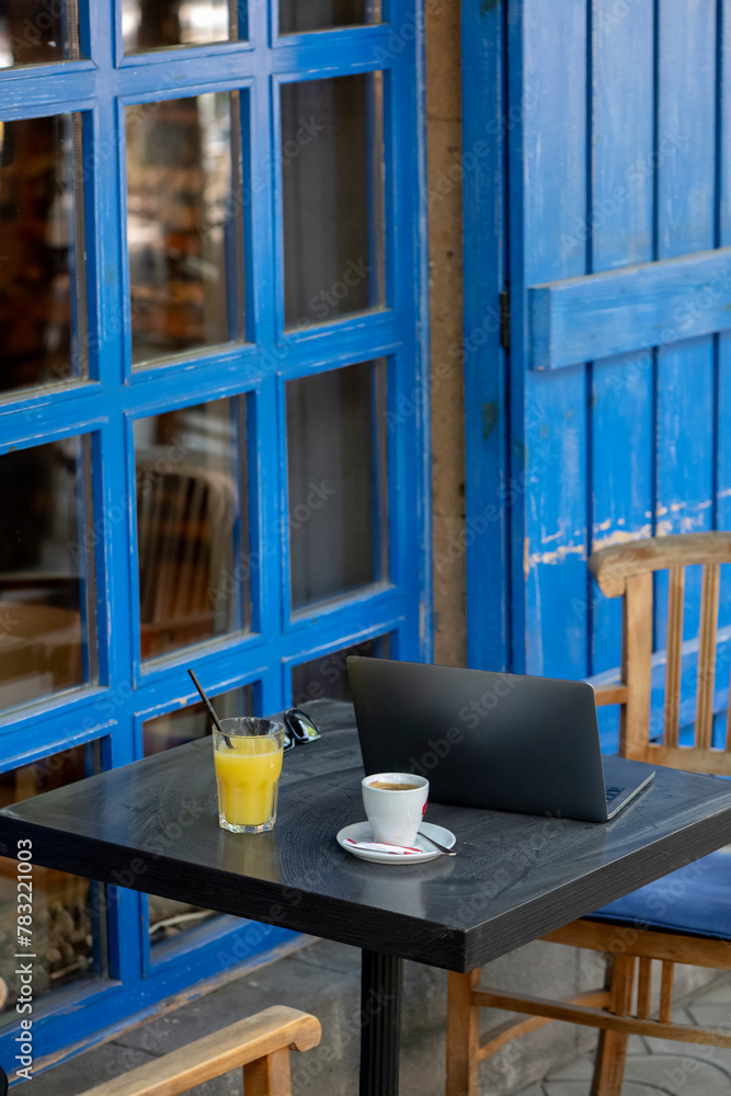 Wooden chairs and tables in a cafe with blue wooden doors.