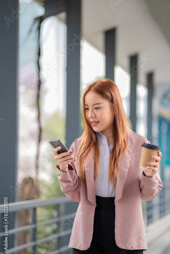 Beautiful Young Asian Woman Going To Work With Coffee Walking Near Office Building. Chilling business woman on phone call while walking