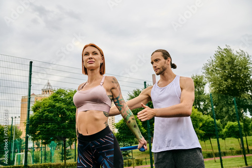 A man and woman, wearing sportswear, standing on a tennis court, ready for a challenging workout with personal trainer. © LIGHTFIELD STUDIOS