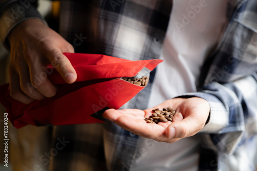 Man Pouring Roasted Coffee Beans Into His Hand From a Red Pouch Package