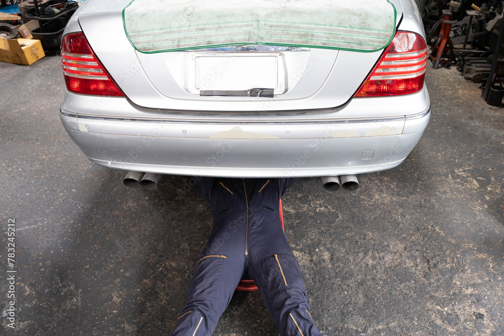 mechanic lying and fixing under car in garage mechanic lying and fixing under car in garage