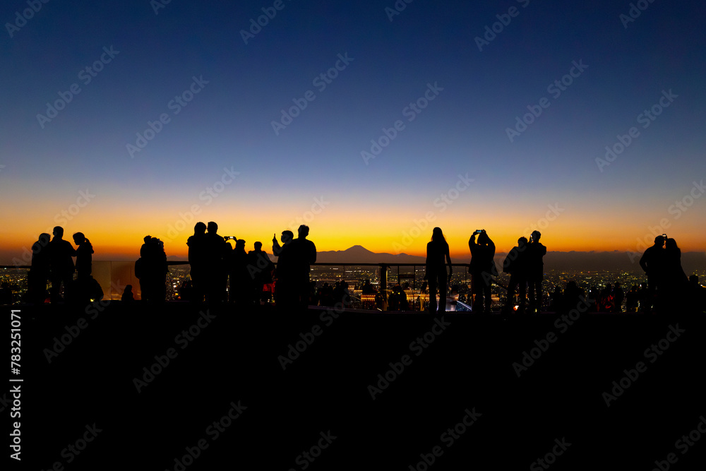 Silhouetted figures observing sunset cityscape