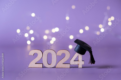 Number 2024 with graduated cap and bokeh lights. Class of 2024 concept © Alina