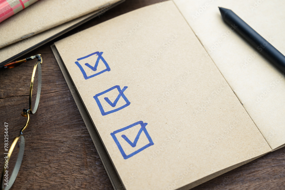 Hand drawing checklists with correct marks on the empty page of a brown ...