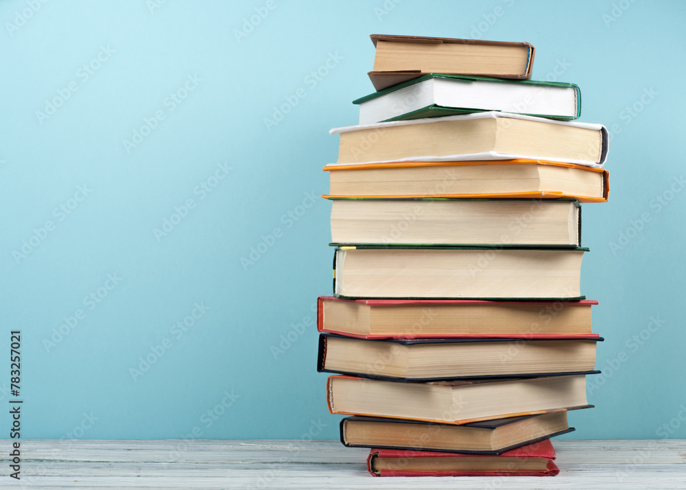 Open stacking book, hardback colorful books on wooden table and blue background. Back to school. Copy space for text. Education business concept. Open stacking book, hardback colorful books on wooden table and blue background. Back to school. Copy space for text. Education business concept.