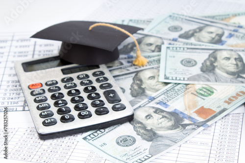 Small graduation cap on calculator, assorted cash.