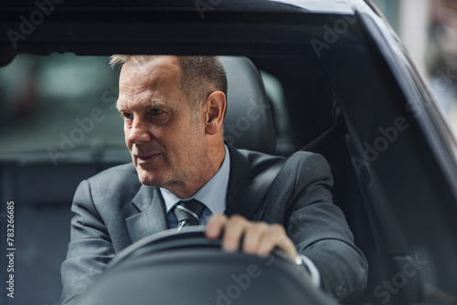 Mature businessman driving to work in his car photo