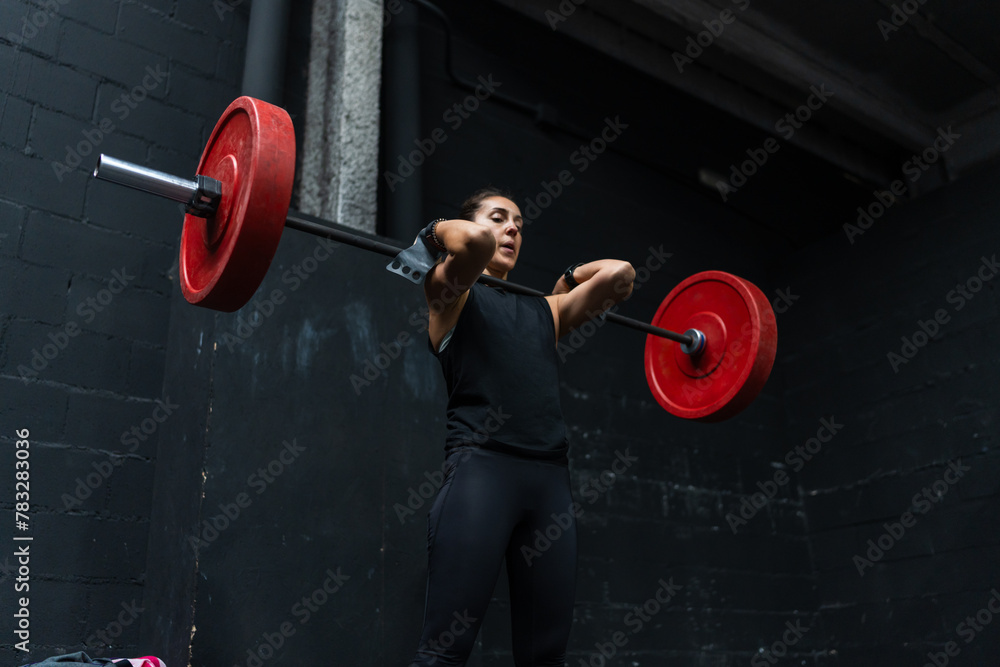 Athletic woman lifting a barbell at the gym Athletic woman lifting a barbell at the gym