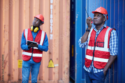 African factory worker or engineer using walkie talkie and talking about work in containers warehouse storage