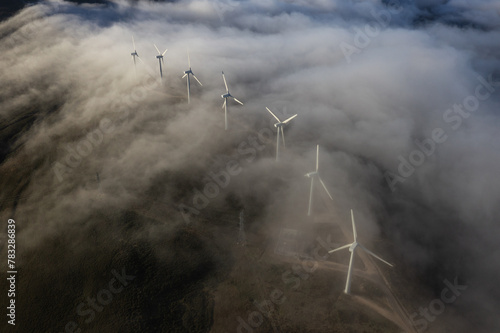 A curvy line of wind turbines and a thin cloud photo