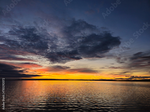 a sunset over a body of water with a cloudy sky