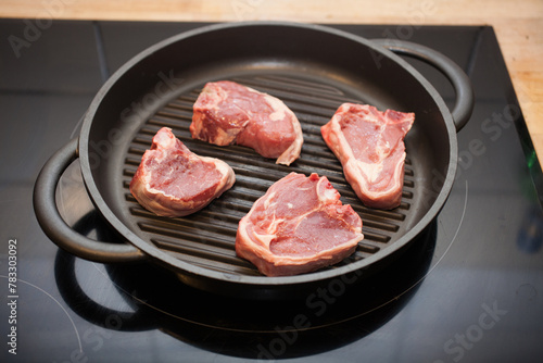 Lamb chops on a griddle pan cooking on a hob