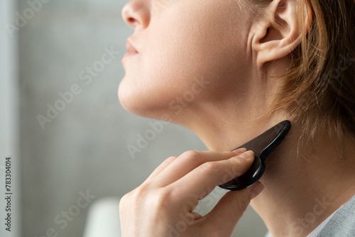 Crop female smoothing neck with gua sha photo