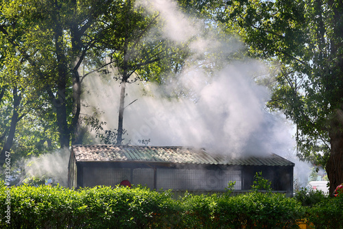 Pożar małego budynku, widoczny dym i płomienie