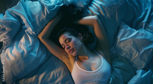 A woman laying in bed with a blue comforter, peacefully sleeping.