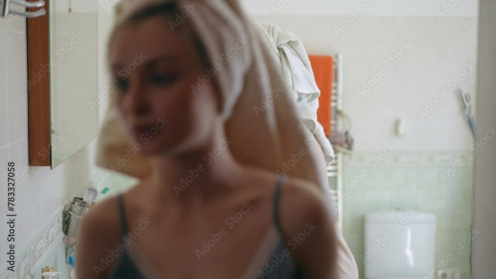Women's secrets and gossip. Three young women with towels on their heads doing makeup while standing in front of a mirror in the bathroom. The girls gossip among themselves while their girlfriend