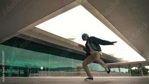 Motion shot of happy hipster practice b boy dance with stylish cloth at building. Dancer enjoy show footstep performance. Modern lifestyle, break dancing. Slow motion. Outdoor sport 2024. Sprightly.