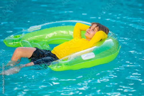Little boy with rubber ring in swimming pool. Summertime fun. Little kid swimming in pool. Kid in swimming pool. Kid relax swim on inflatable ring. Summer vacation concept.