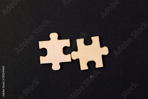 Two pieces of a puzzle on a black background Business concept