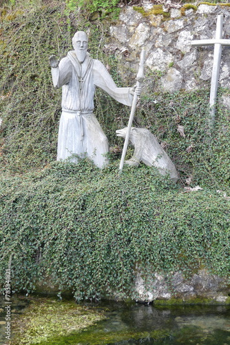 Gallusfigur  mit Wanderstab und Bär am Rand des Quellbeckens der Gallusquelle in Hermentingen bei Veringenstadt photo