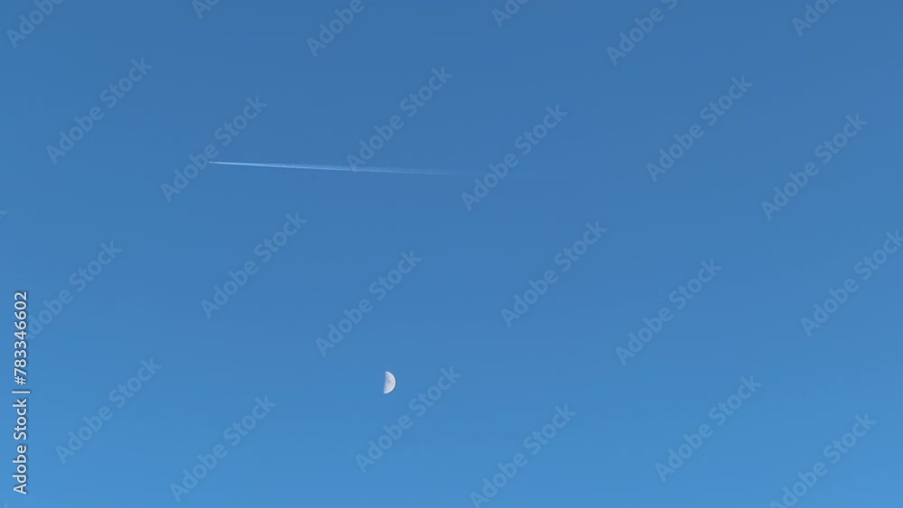 Flying commercial airplane and moon over sunny blue sky Flying commercial airplane and moon over sunny blue sky