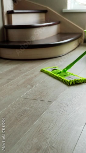Washing the laminate floor with a mop. Housekeeper with mop and bucket is cleaning floor at home. Floor care concept. Vertical video