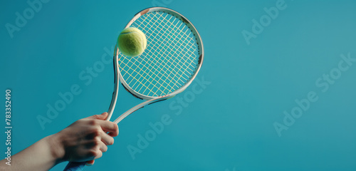 Tennis player is holding racquet and hitting ball on blue background