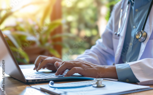 A doctor typing on a laptop keyboard, updating patient medical records or consulting photo