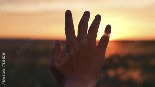 Woman stretched out hand sunset silhouette. Girl traveler in field dreams prays contemplates environment beauty sunlight shines through fingers. Connection with spiritual religious hope faith belief.