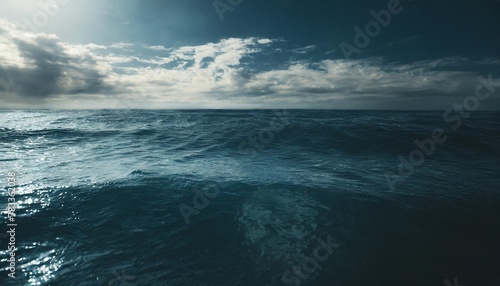 closeup surface of calm ocean blue sea water with day light and clouds abstract background texture