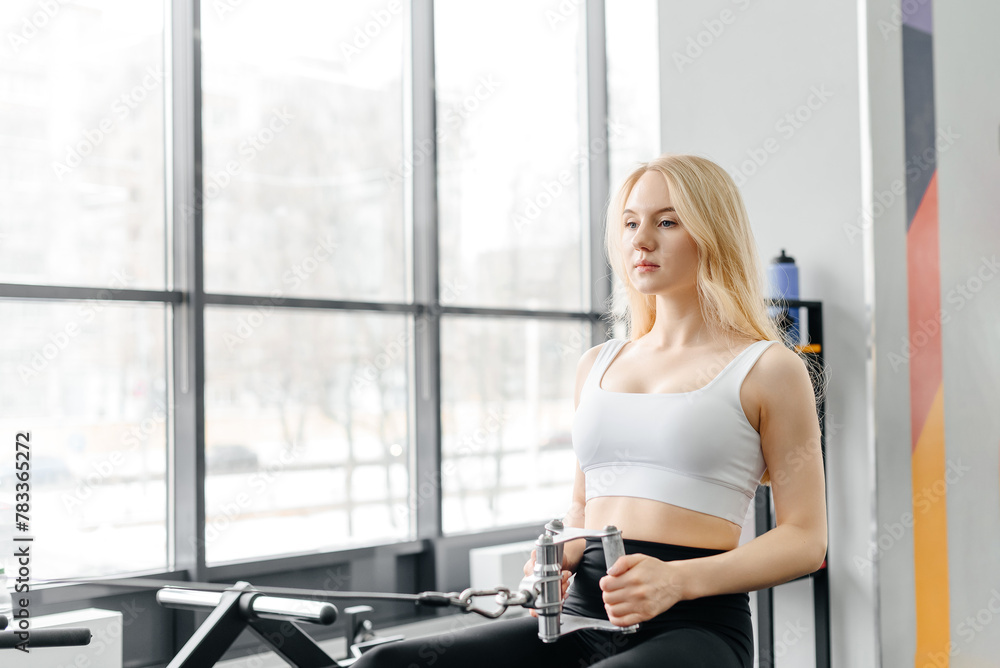young athletic caucasian woman trains in fitness gym, thrust in block simulator, blonde girl in white top and black leggings, healthy lifestyle concept young athletic caucasian woman trains in fitness gym, thrust in block simulator, blonde girl in white top and black leggings, healthy lifestyle concept