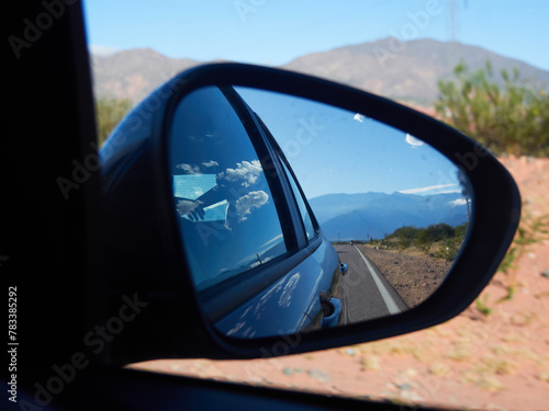 Route viewed through a rear-view mirror on the dessert in a sunny day