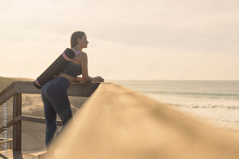 A girl is preparing to practice outdoor yoga on the ocean. Calmness and relax. Background with ocean view and yoga trainer.
