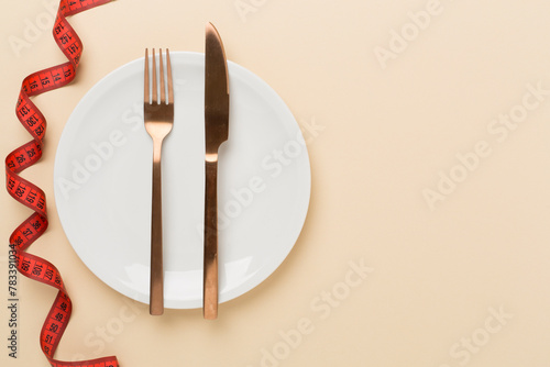 Measuring tape with empty plate on color background, top, view. Weight loss concept