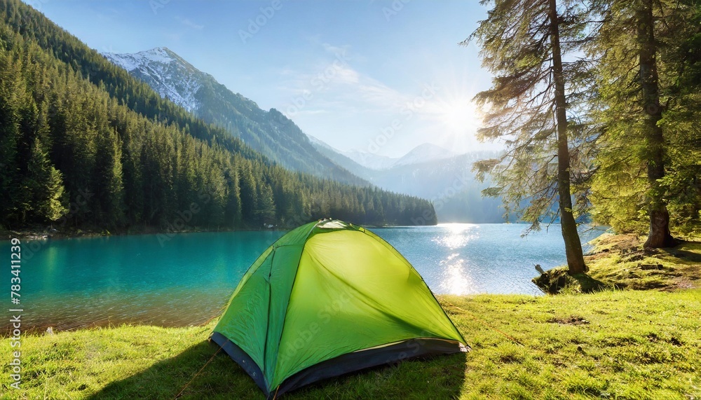 green tent near forest lake in the mountains with blue water and morning light