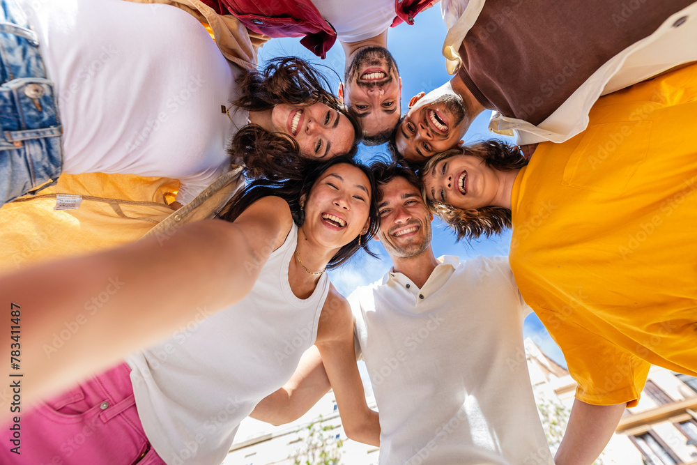 © Xavier Lorenzo - Group of young people taking a selfie standing in a circle outdoors. Youth community and friendship concept with diverse boys and girls laughing and celebrating together.