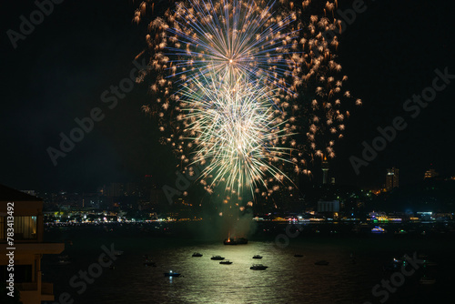 Beautiful colorful show fireworks reflection on sea with boats over city background. Festival abstract fireballs bright on black sky night reflections beach sea. Symbol celebration holiday fireworks