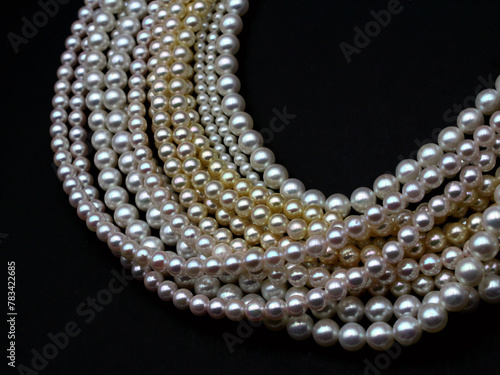 Expensive and luxurious Japanese saltwater Akoya pearls on strands of white, pink and golden organic gems ready to be made into necklaces and sold in jewelry store.