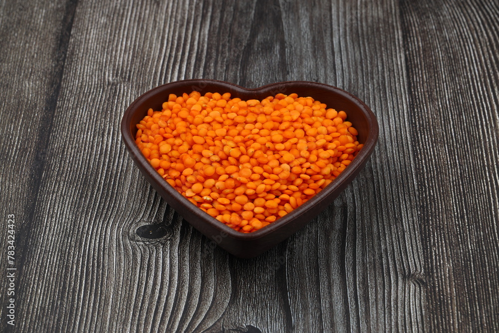 Pile red lentil in shape of heart isolated on wooden background. Top view. Flat lay. Vegetarian and vegan diet. High content of B vitamins in Red lentils. healthy Superfood Pile red lentil in shape of heart isolated on wooden background. Top view. Flat lay. Vegetarian and vegan diet. High content of B vitamins in Red lentils. healthy Superfood