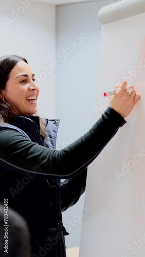 Young engineer woman writing on a whiteboard during a meeting. Person leading team.