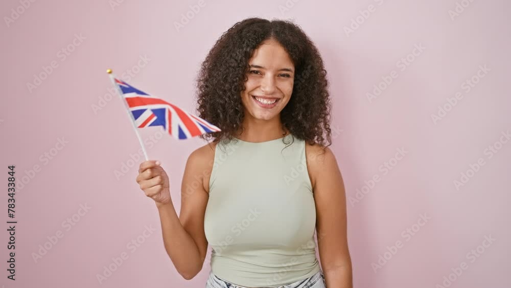 Radiant young hispanic woman, beautiful and confident, joyfully holding a united kingdom flag, isolated over a fun pink background Radiant young hispanic woman, beautiful and confident, joyfully holding a united kingdom flag, isolated over a fun pink background