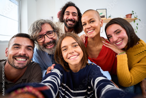 Joyful Caucasian family smiling hugging taking a selfie photo indoor. Three generations Caucasian people looking at front camera at home. Happy people relations in domestic life