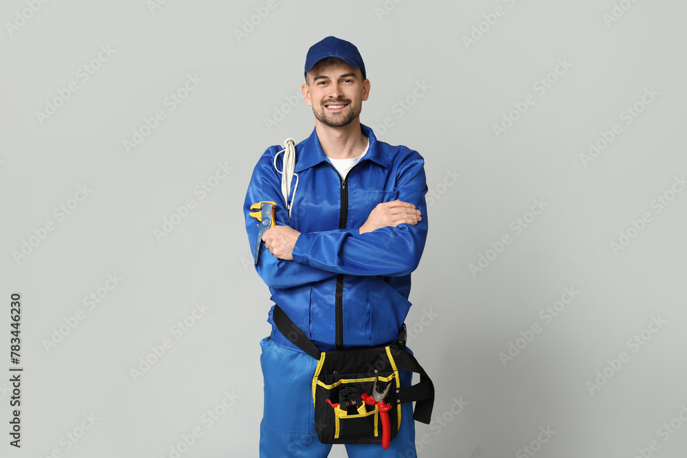Portrait of male electrician with wires and crimper on grey background Portrait of male electrician with wires and crimper on grey background